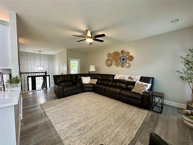 living area featuring a ceiling fan, dark wood-style flooring, and baseboards