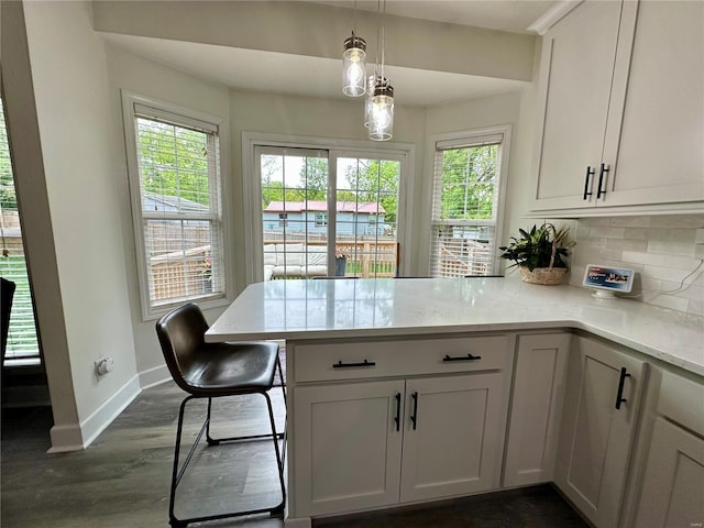 kitchen featuring a peninsula, decorative backsplash, baseboards, and a healthy amount of sunlight