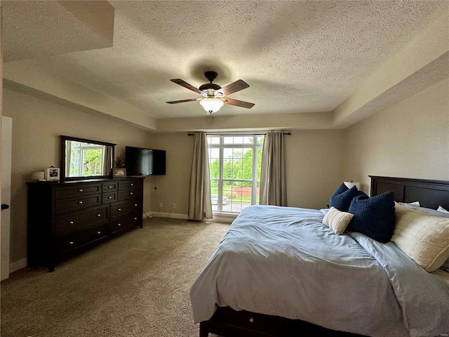 bedroom with light colored carpet, a textured ceiling, baseboards, and a ceiling fan