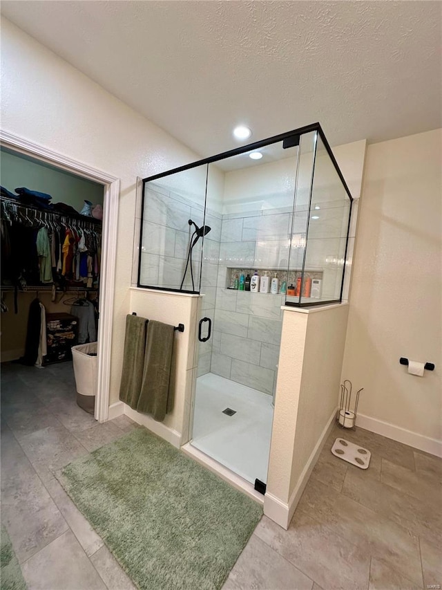 bathroom featuring tile patterned flooring, a spacious closet, baseboards, and a shower stall