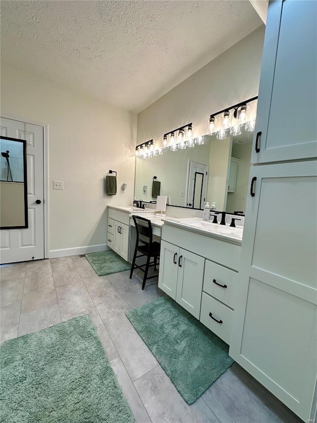 full bathroom featuring baseboards, tile patterned flooring, two vanities, and a textured ceiling