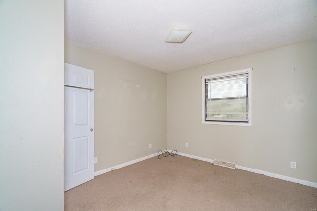 spare room with light colored carpet, baseboards, and visible vents