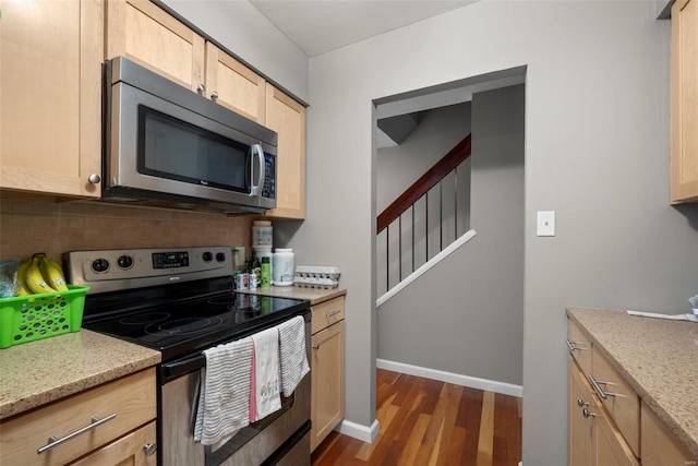 kitchen with light brown cabinets, dark wood-style floors, light stone counters, backsplash, and stainless steel appliances