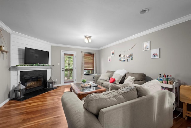 living area featuring baseboards, ornamental molding, a fireplace, and wood finished floors