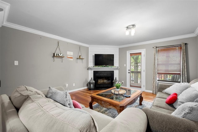 living area with baseboards, ornamental molding, wood finished floors, and a fireplace