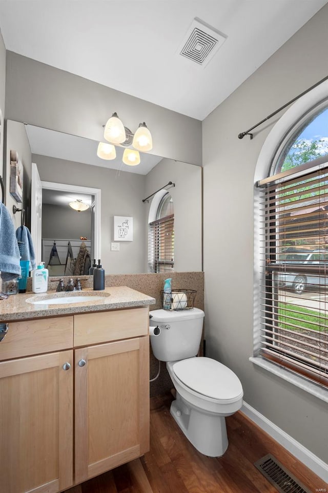 bathroom with visible vents, wood finished floors, toilet, and vanity