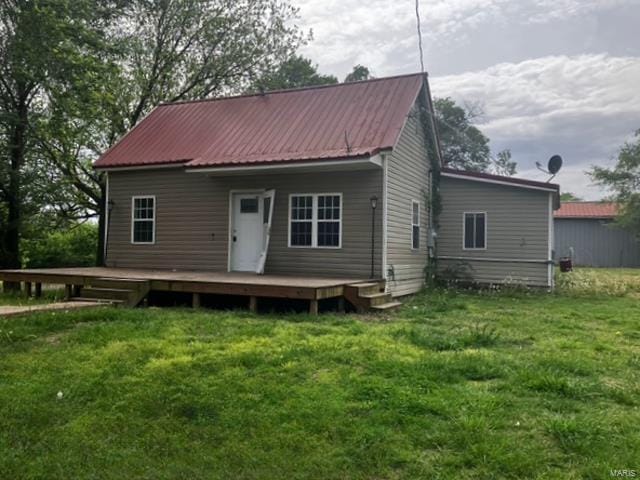 back of property featuring a yard, a deck, and metal roof