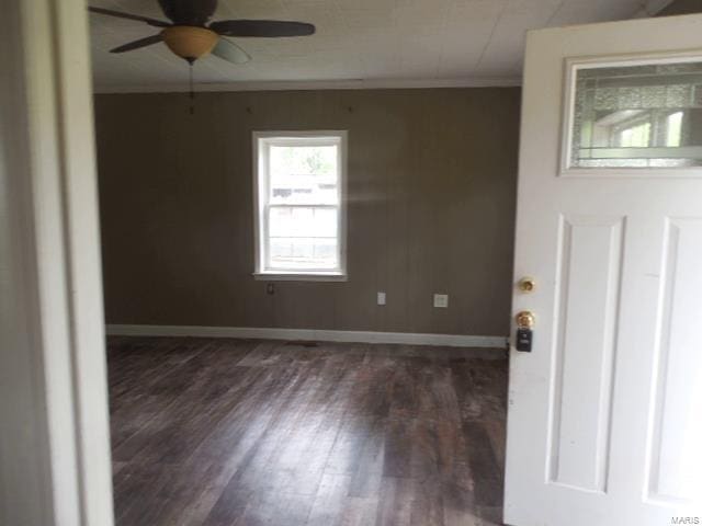 unfurnished room featuring crown molding, a ceiling fan, baseboards, and dark wood-type flooring