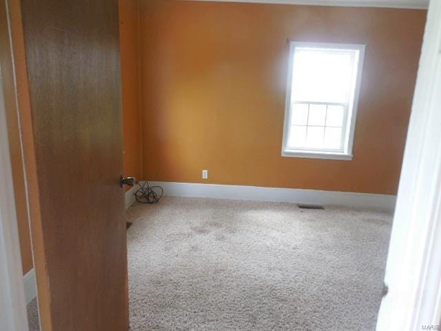 carpeted spare room featuring baseboards and visible vents