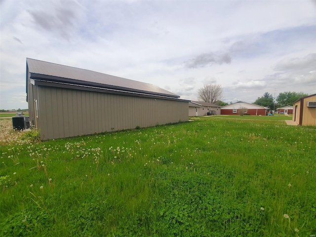 view of yard featuring central AC unit, a pole building, and an outbuilding