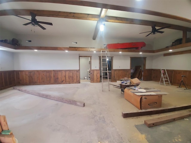 basement featuring a wainscoted wall, ceiling fan, and wood walls