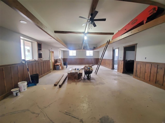interior space with a wainscoted wall, a ceiling fan, and wood walls