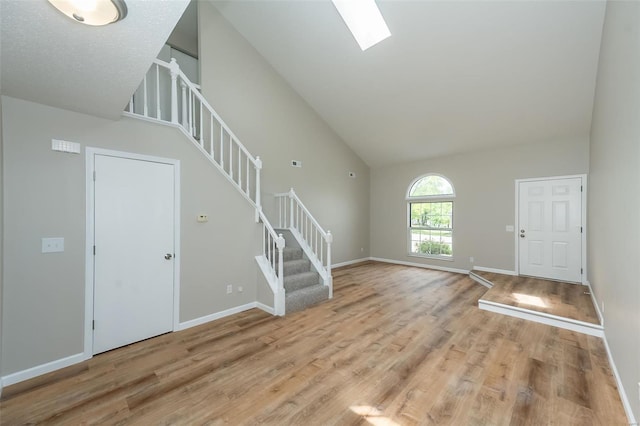 foyer with stairs, a skylight, baseboards, and light wood-type flooring