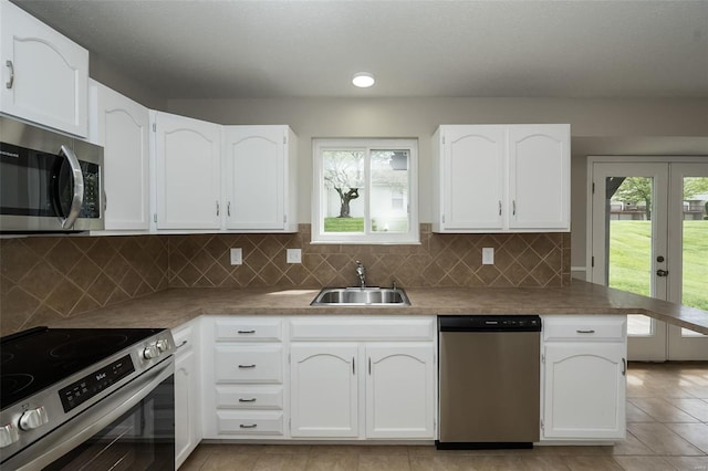 kitchen with white cabinets, light tile patterned floors, appliances with stainless steel finishes, and a sink