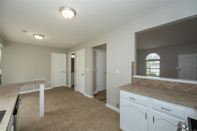 kitchen with light countertops, white cabinetry, baseboards, and visible vents