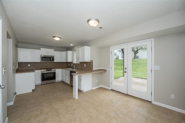 kitchen featuring visible vents, white cabinetry, a sink, backsplash, and stainless steel appliances