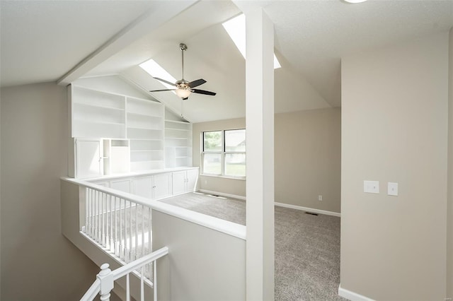 hallway with baseboards, lofted ceiling with beams, carpet, and an upstairs landing