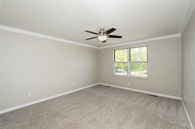 empty room featuring crown molding, visible vents, carpet flooring, baseboards, and a ceiling fan
