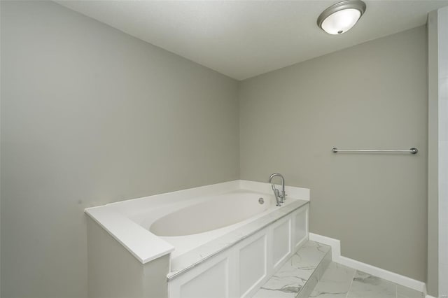 bathroom with baseboards, marble finish floor, and a garden tub