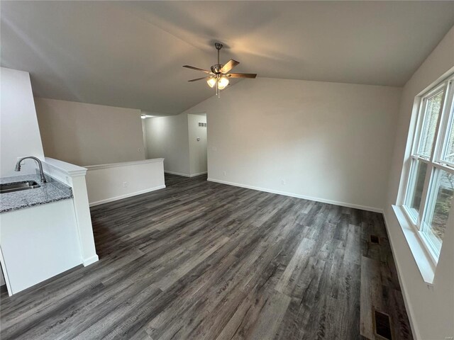 unfurnished living room with a sink, a ceiling fan, baseboards, dark wood-type flooring, and vaulted ceiling