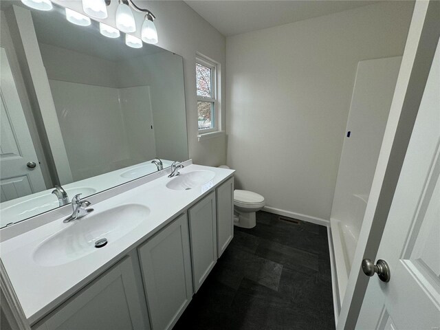 full bathroom with double vanity, a sink, and toilet