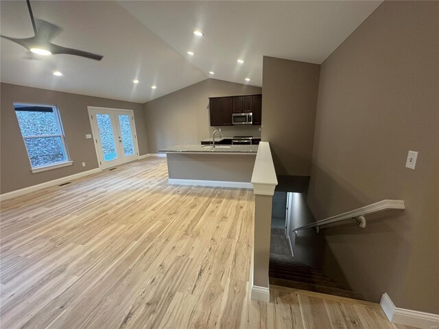 kitchen featuring ceiling fan, light countertops, stainless steel microwave, light wood-style flooring, and vaulted ceiling