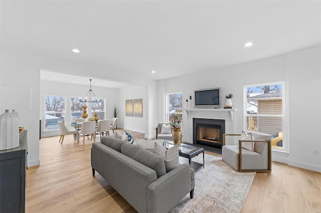 living room with a fireplace, baseboards, recessed lighting, a chandelier, and light wood finished floors