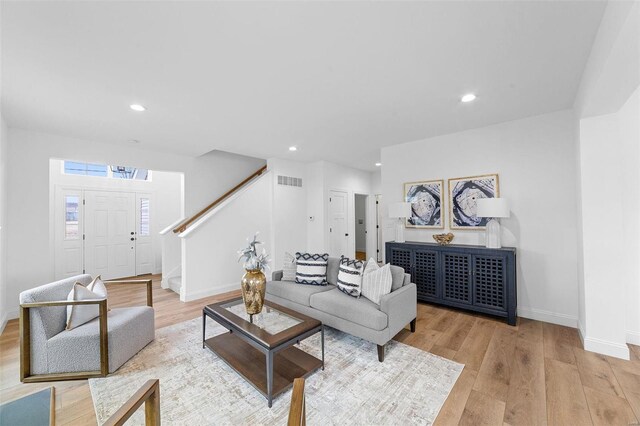 living area with visible vents, baseboards, stairway, and light wood-type flooring