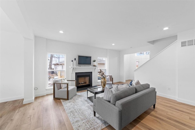 living area with recessed lighting, visible vents, a fireplace with flush hearth, and light wood-style floors