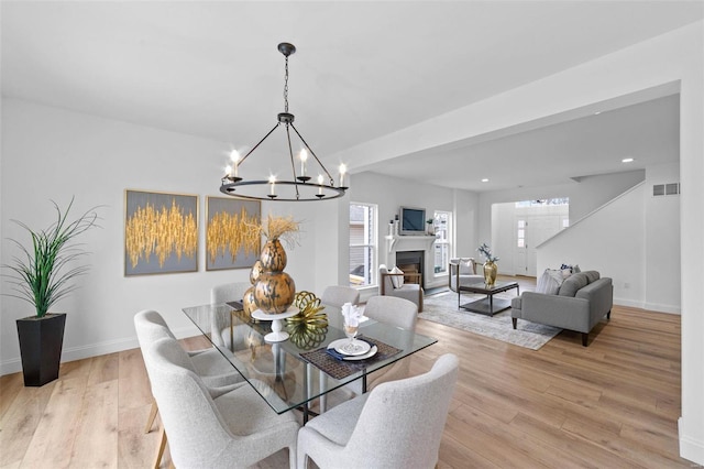dining room featuring baseboards, visible vents, light wood-type flooring, and a chandelier