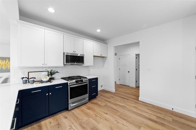 kitchen featuring decorative backsplash, light countertops, white cabinetry, stainless steel appliances, and blue cabinetry