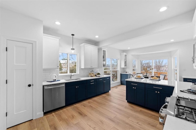 kitchen with a sink, light countertops, stainless steel appliances, white cabinetry, and backsplash