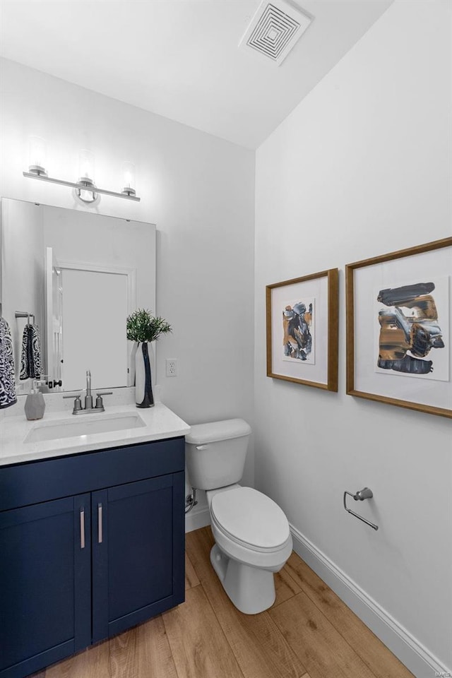 bathroom featuring visible vents, vanity, wood finished floors, toilet, and baseboards