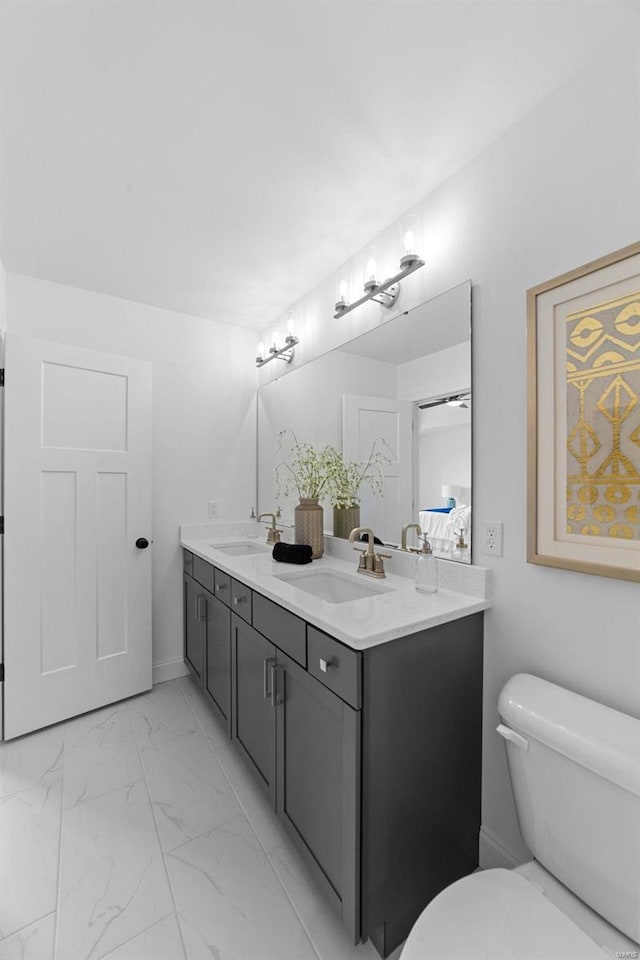 bathroom with double vanity, toilet, a sink, and marble finish floor