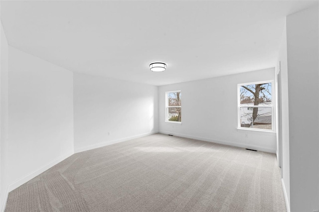 unfurnished room featuring baseboards, visible vents, and light carpet
