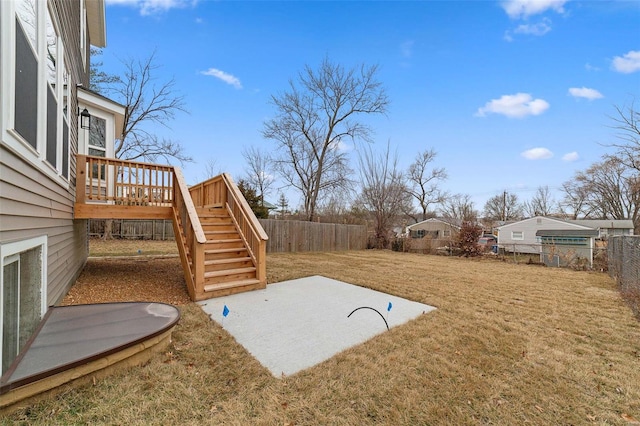 view of yard with stairs, a fenced backyard, a wooden deck, and a patio