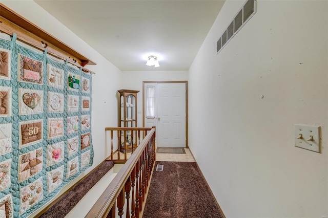 hall featuring an upstairs landing, visible vents, and light colored carpet
