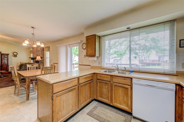 kitchen featuring a sink, a peninsula, light countertops, white dishwasher, and hanging light fixtures