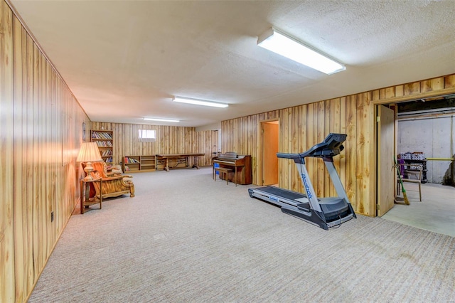 workout room featuring carpet flooring, a textured ceiling, and wooden walls