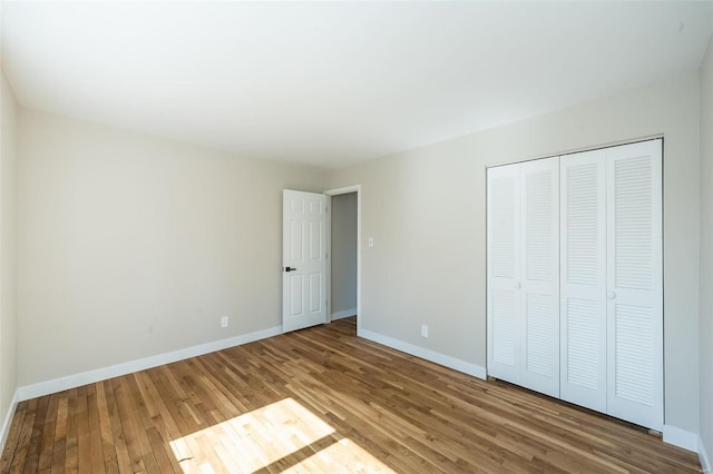 unfurnished bedroom with baseboards, wood finished floors, and a closet