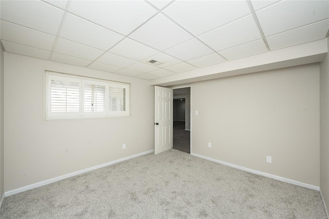 carpeted empty room with baseboards, visible vents, and a drop ceiling