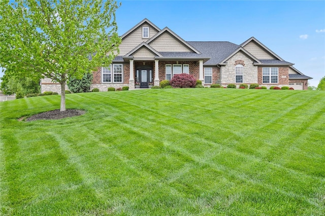 craftsman-style home featuring a shingled roof, brick siding, and a front yard