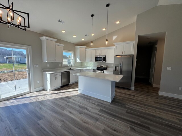 kitchen with appliances with stainless steel finishes, a kitchen island, dark wood-style flooring, and white cabinetry