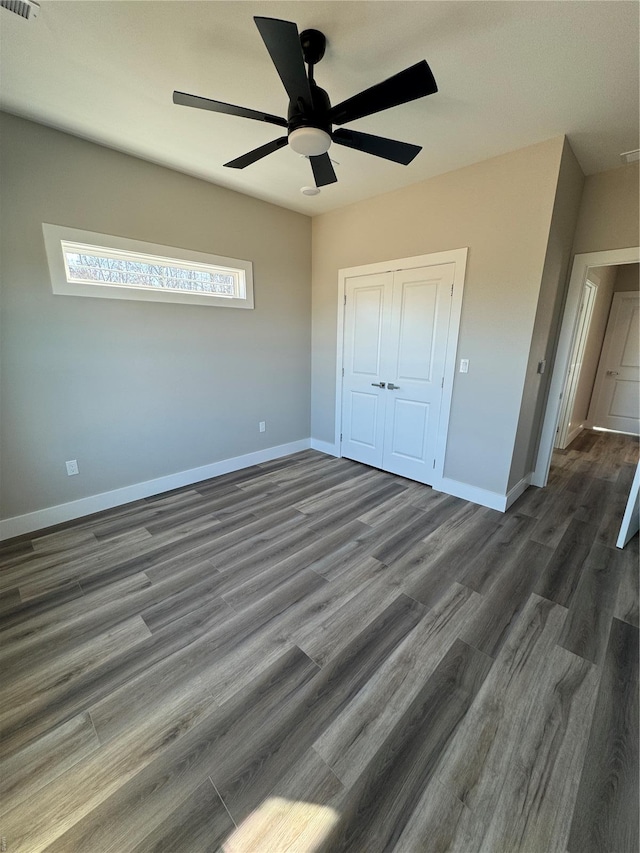 unfurnished bedroom with a closet, wood finished floors, baseboards, and a ceiling fan