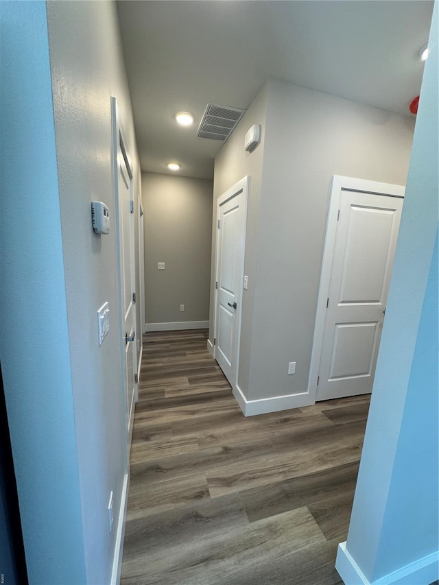 hallway with wood finished floors, visible vents, baseboards, and recessed lighting