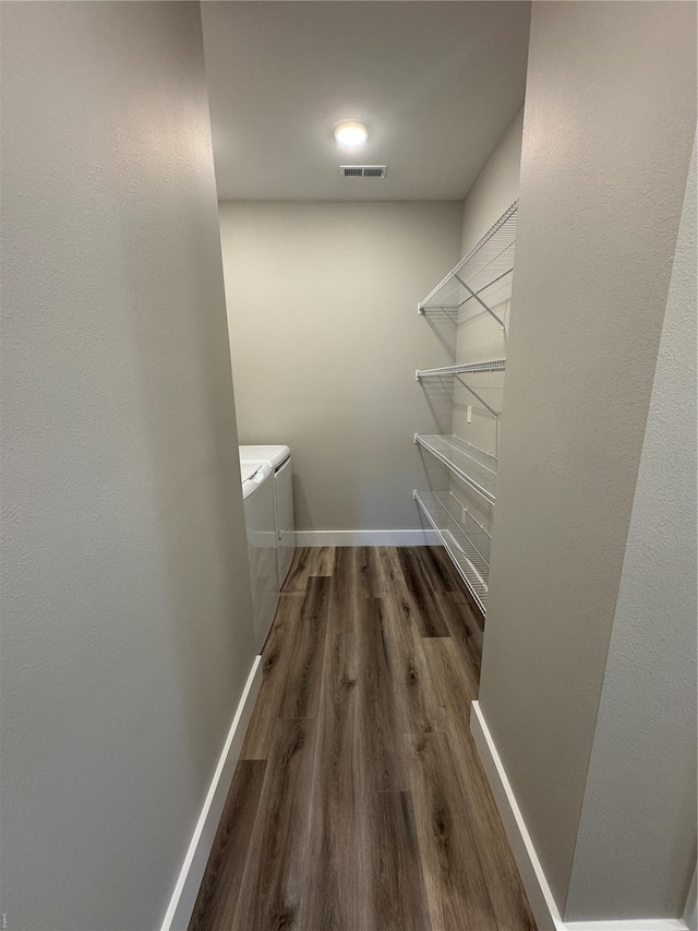 walk in closet with washing machine and clothes dryer, visible vents, and wood finished floors