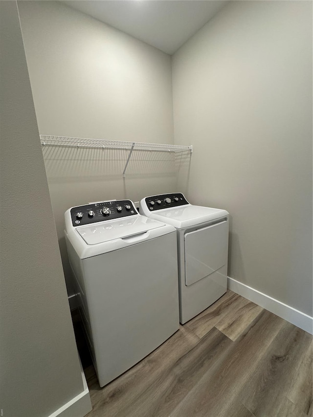 laundry area featuring washer and clothes dryer, light wood finished floors, baseboards, and laundry area