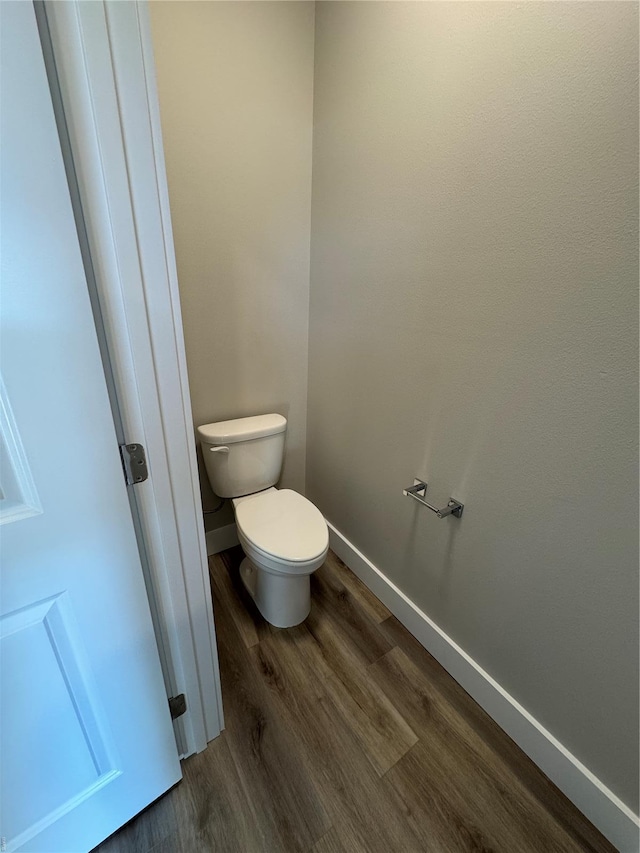 bathroom with toilet, baseboards, and wood finished floors