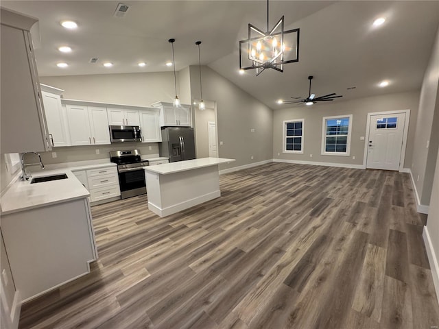 kitchen featuring a center island, visible vents, a sink, ceiling fan with notable chandelier, and stainless steel appliances