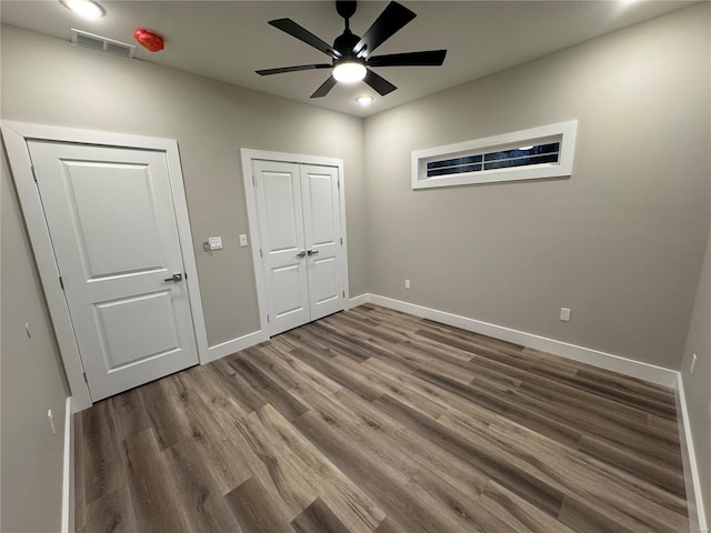 unfurnished bedroom featuring wood finished floors, a ceiling fan, a closet, visible vents, and baseboards